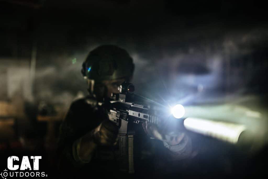 Operator in tactical gear holding AR-15 with SureFire M340C-PRO Mini Scout Light Pro illuminated at night