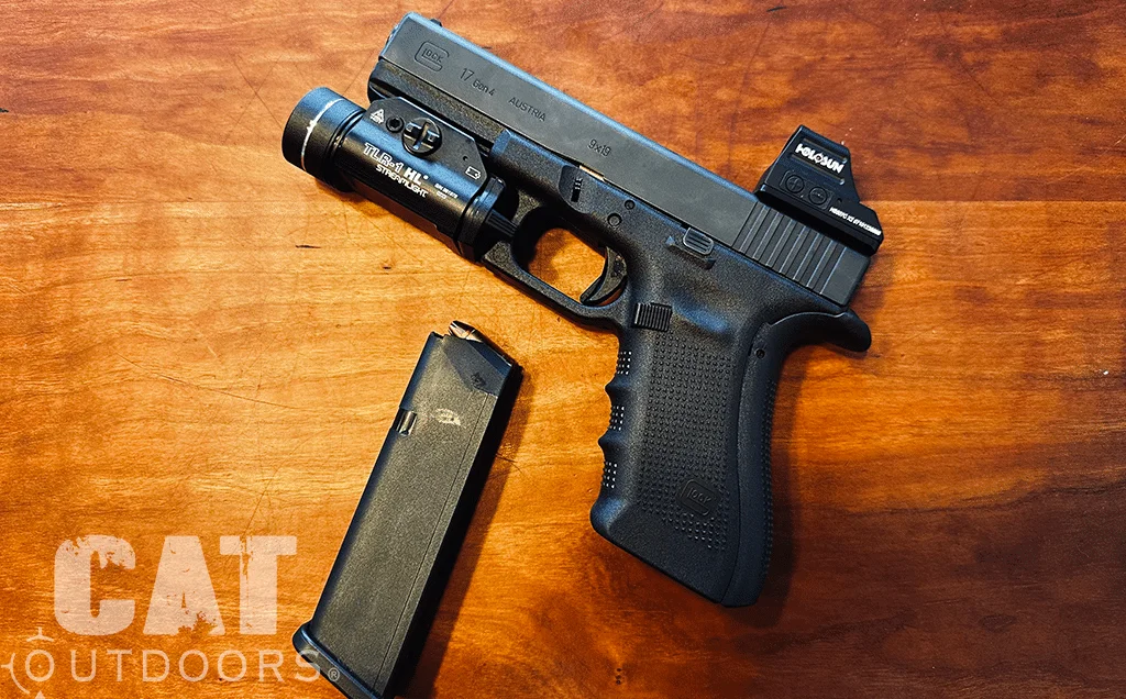 Glock 17 Gen 4 with finger groove grip, weapon light and red dot beside a spare magazine