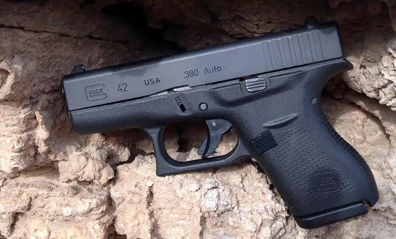 Glock 42 in .380 Auto propped against rough tan sandstone, left side view