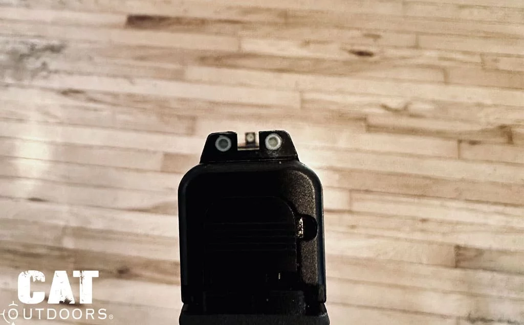 Rear view down the 43X slide showing the three-dot Trijicon night sight picture against pale wood