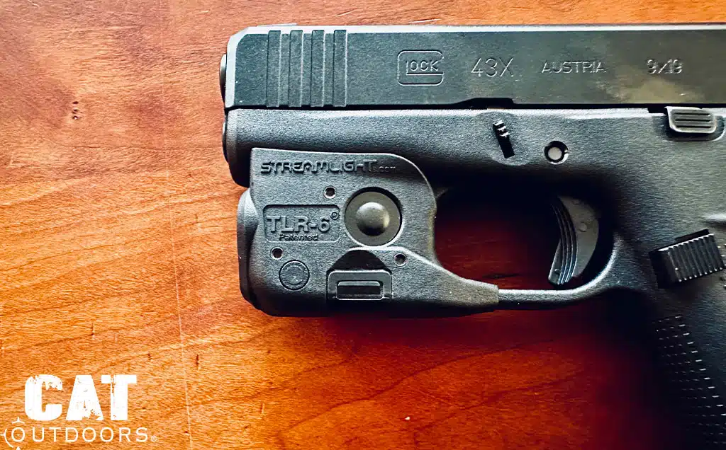 Streamlight TLR-6 light clamped around the trigger guard of a 43X, close up on wood
