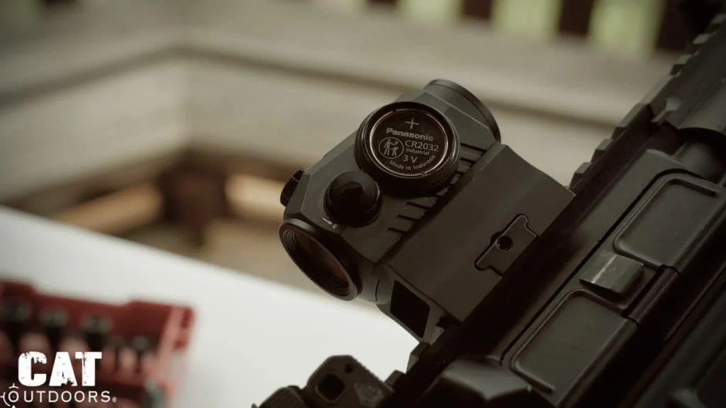 Romeo 5 on the upper rail with its battery cap off and the CR2032 coin cell exposed