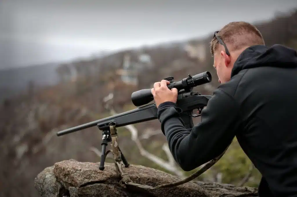 Man looking through scope on a mountain side
