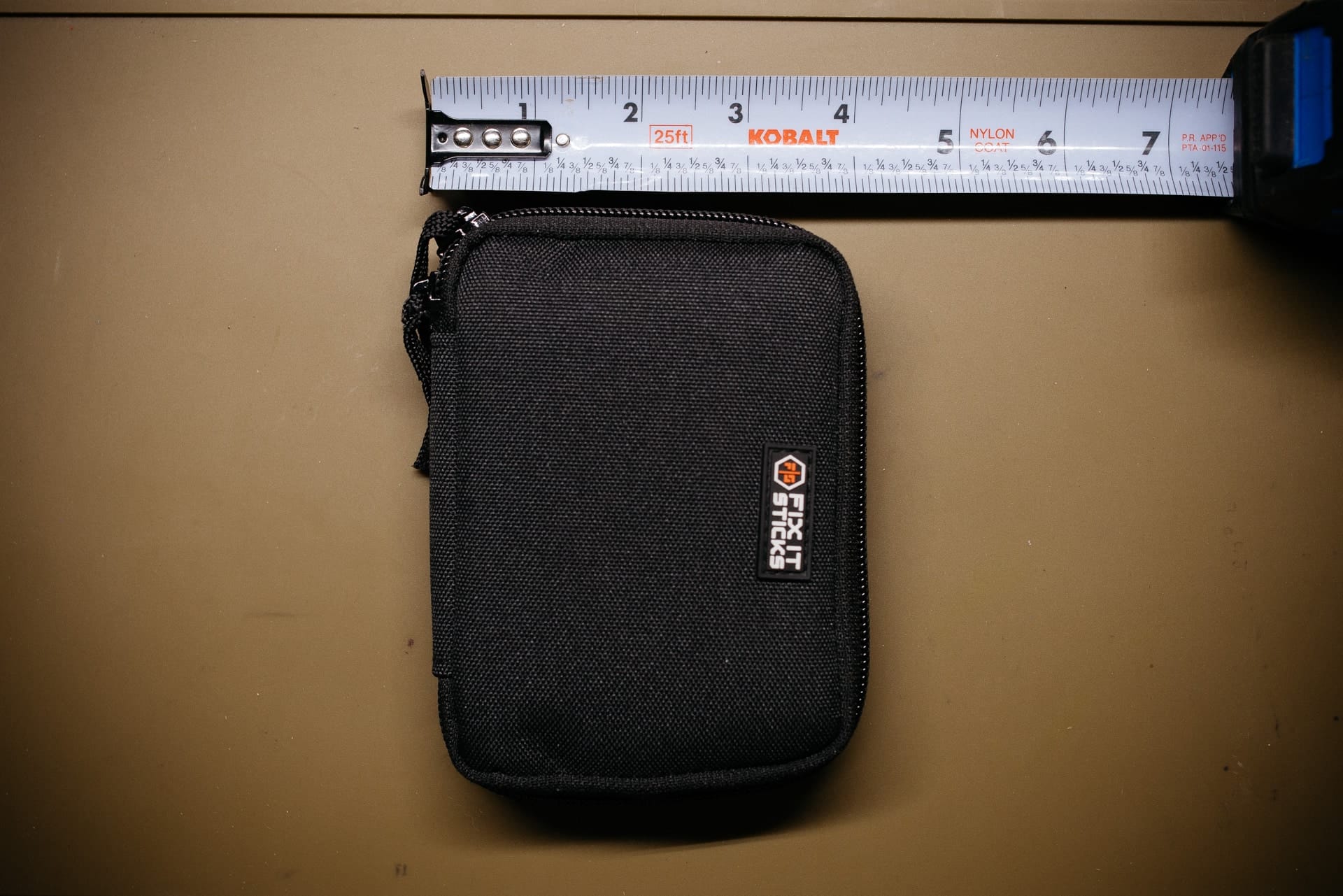 Fix It Sticks case next to a tape measure, about 4 by 5 inches