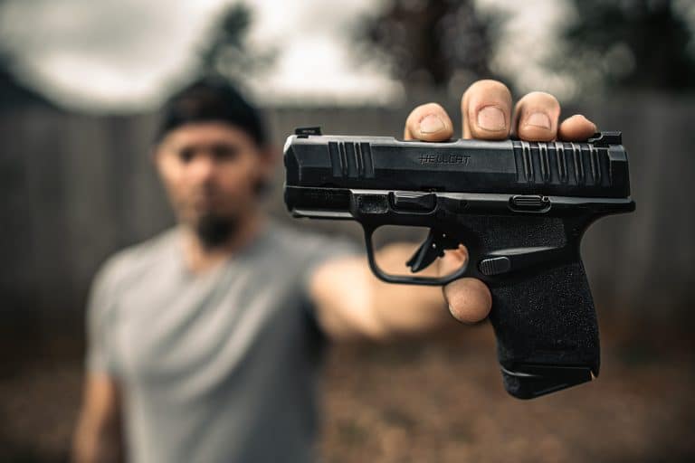 Brad holding the Springfield Hellcat 9mm toward the camera in an outdoor backyard setting with the slide engraving sharp and clear