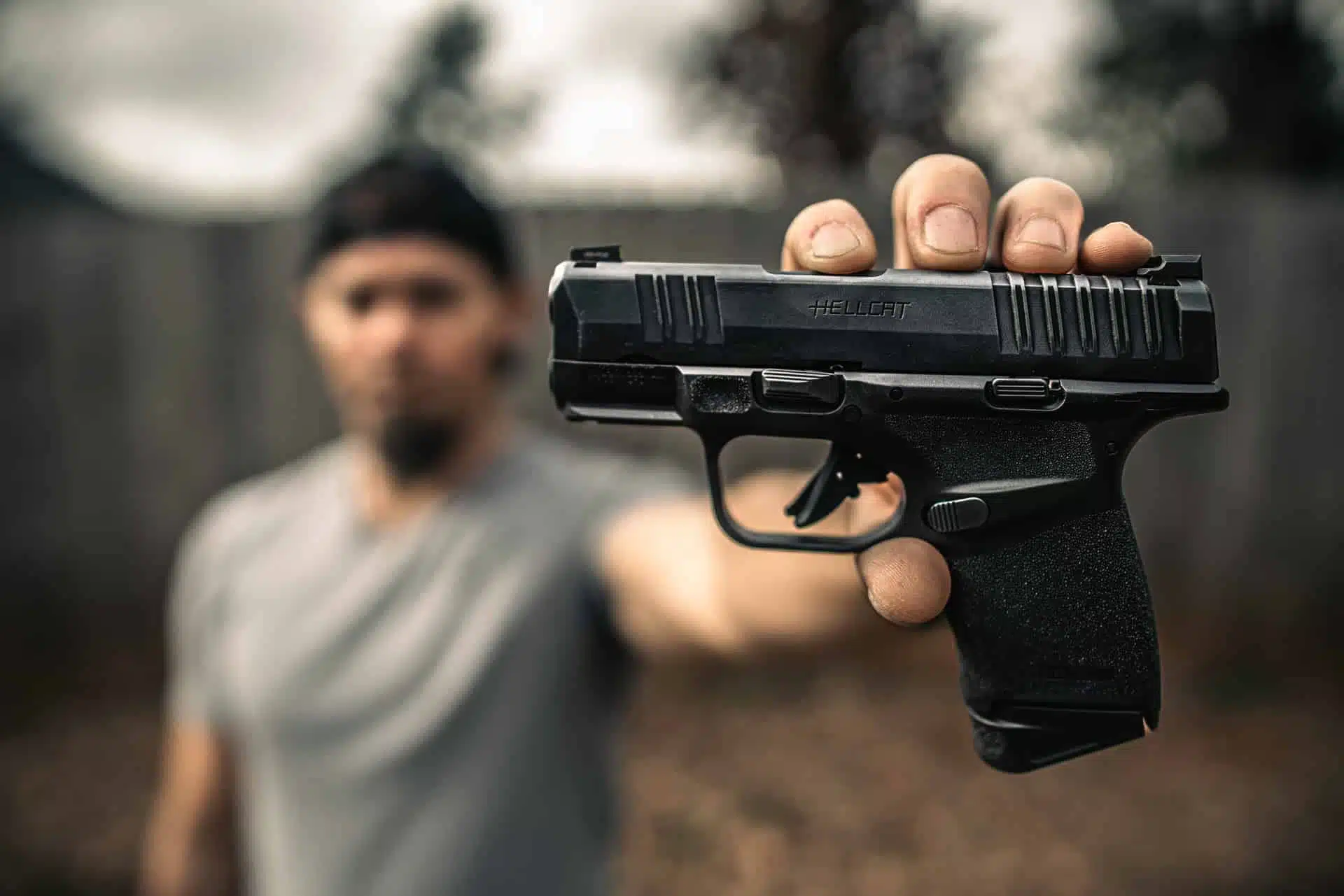 Brad holding the Springfield Hellcat 9mm toward the camera in an outdoor backyard setting with the slide engraving sharp and clear