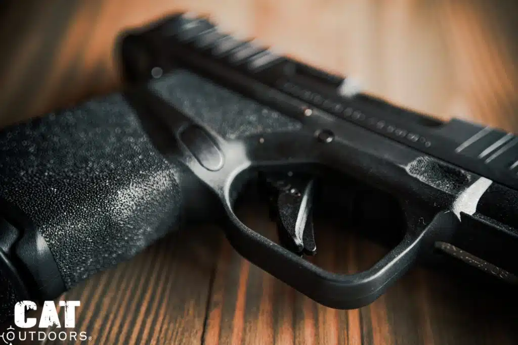 Macro close-up of the Springfield Hellcat flat-faced trigger with integrated blade safety and Adaptive Grip Texture in extreme detail