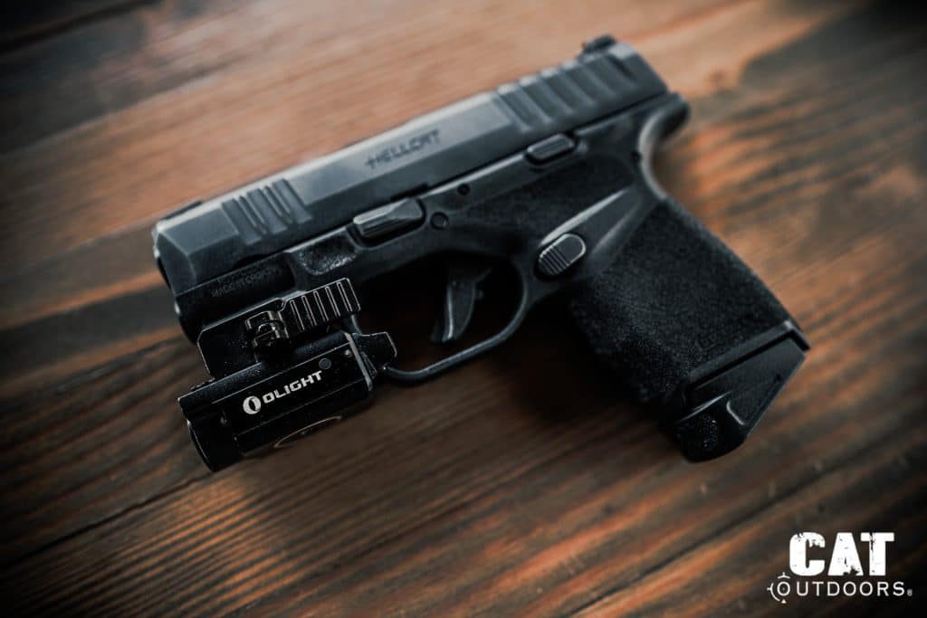 Springfield Hellcat with Olight Baldr Mini weapon light mounted to the accessory rail and 13-round extended magazine inserted