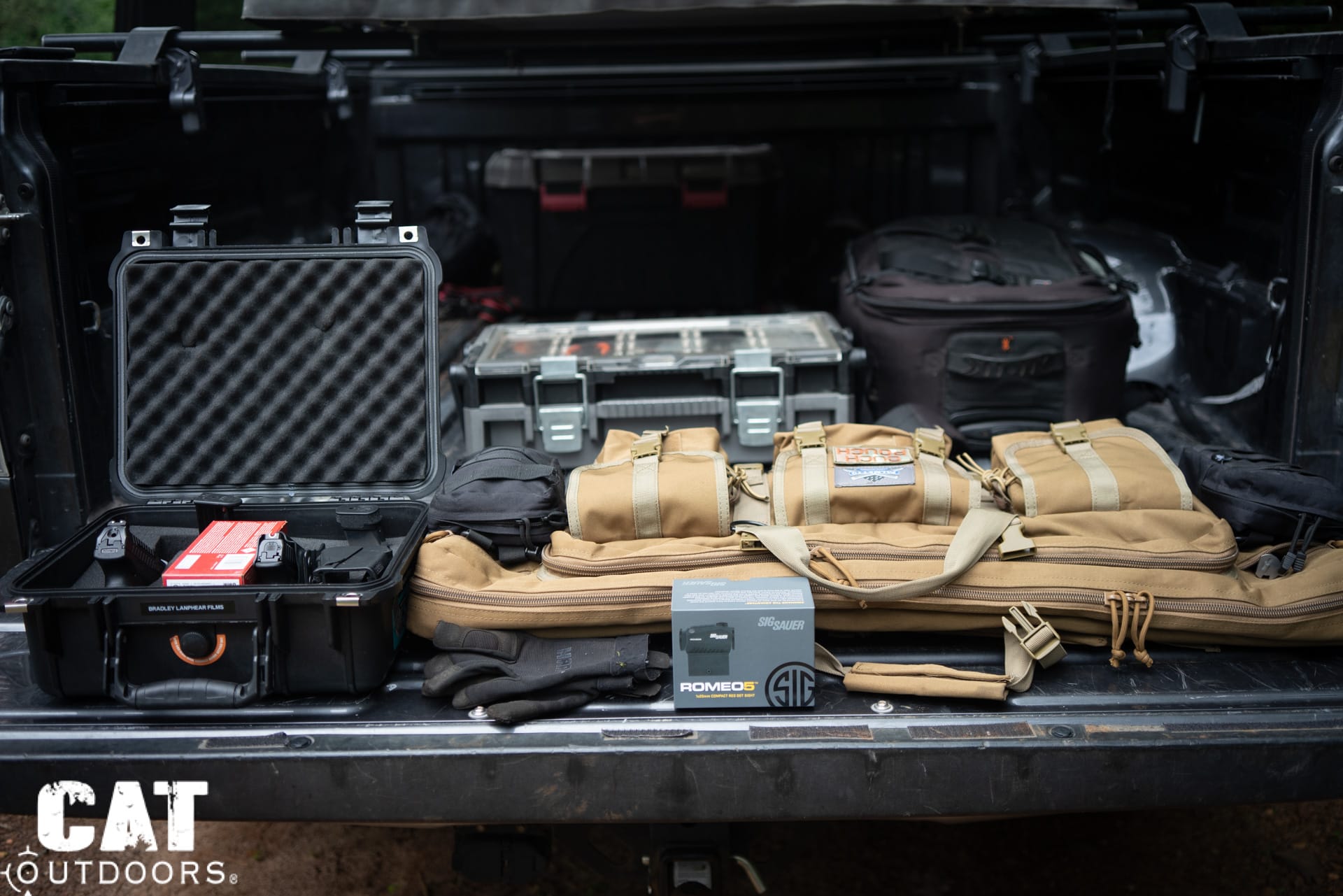 CAT Outdoors tailgate loadout with Pelican case, Magpul rifle cases, Sig Sauer Romeo5 red dot optic, and tactical gear