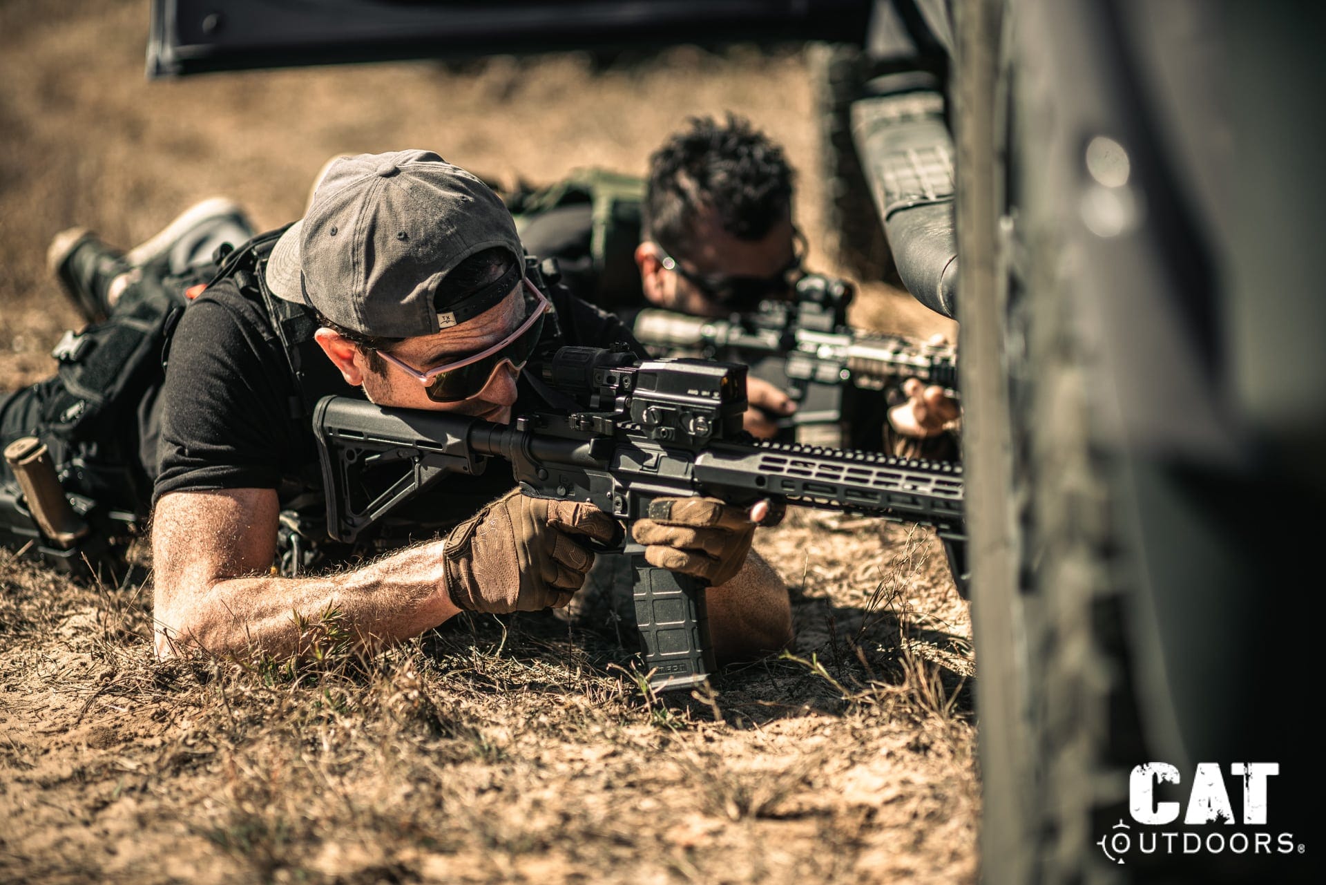 CAT Outdoors team field-testing AR-15 rifles prone behind vehicle cover