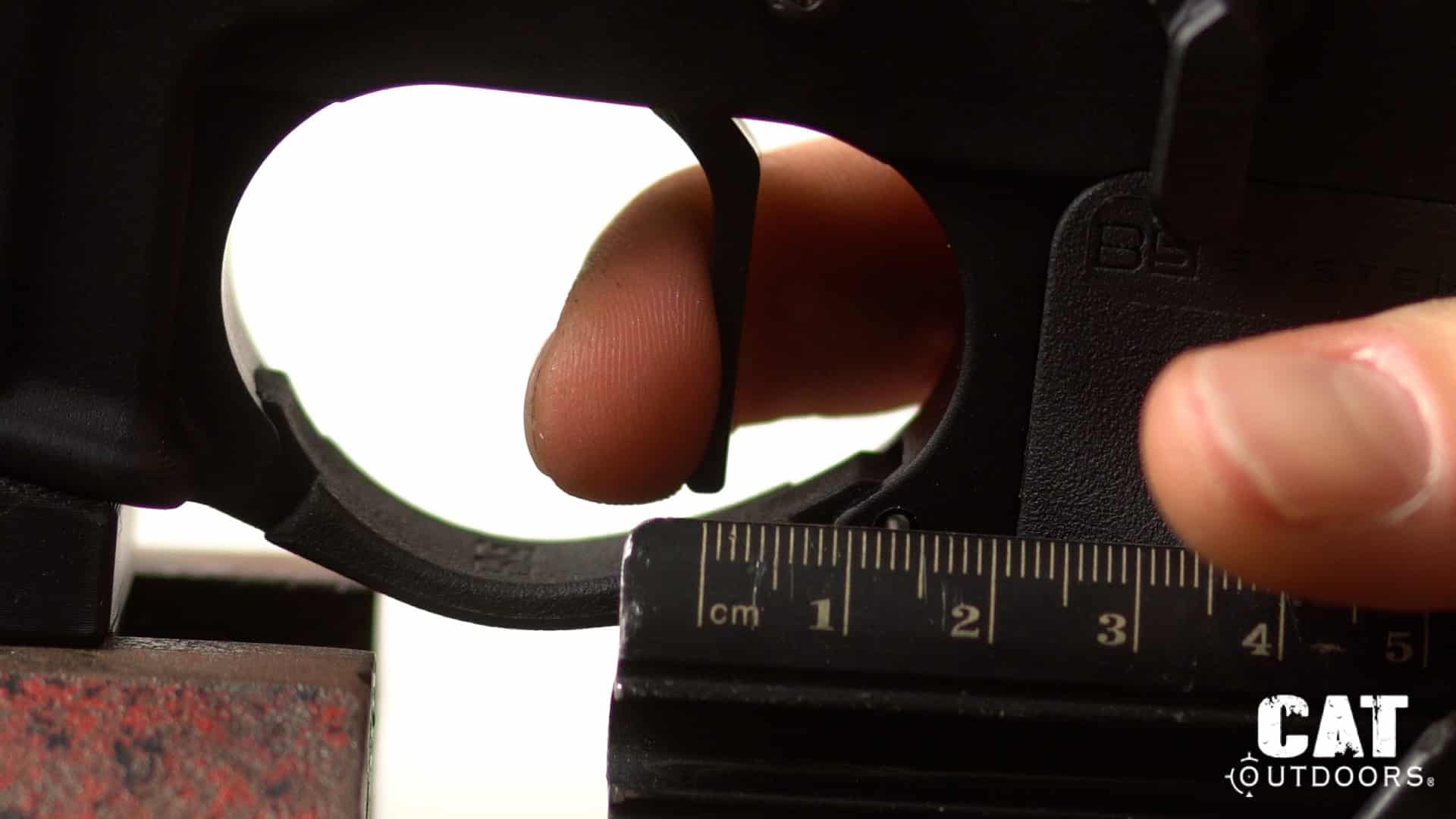 TriggerTech Diamond trigger pulled fully rearward against a metric ruler showing just 1.5 mm of total travel