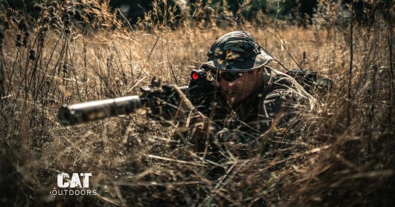 Prone shooter in tall grass with a suppressed AR-15