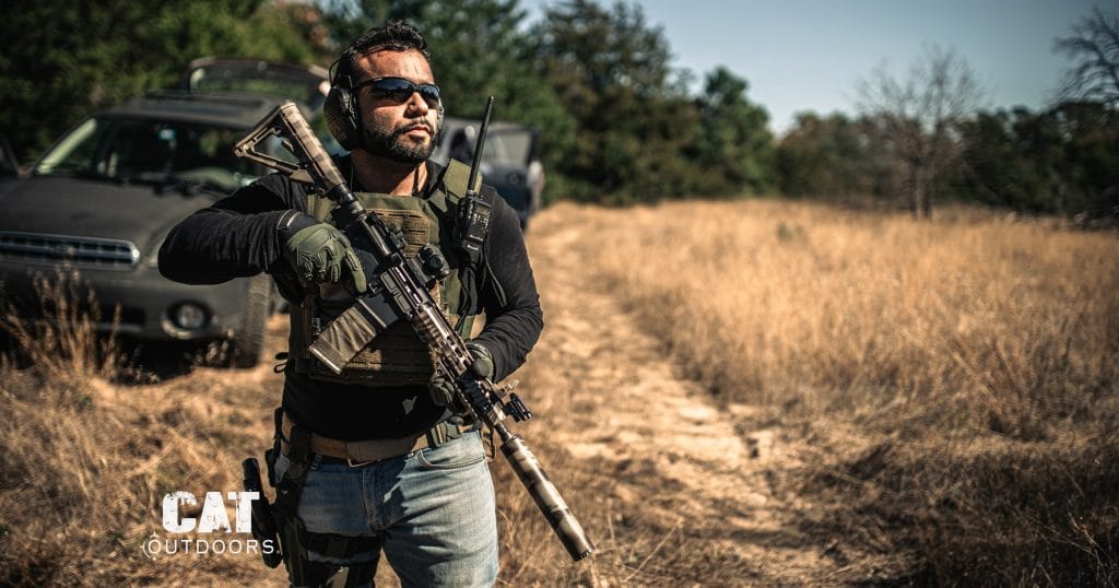 Shooter carrying a suppressed AR-15 rifle in the field