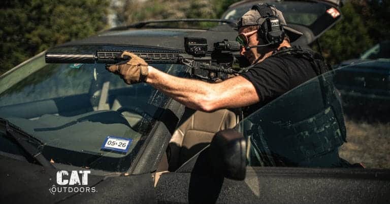 Shooter with a semi-automatic AR-15 rifle braced over a vehicle hood