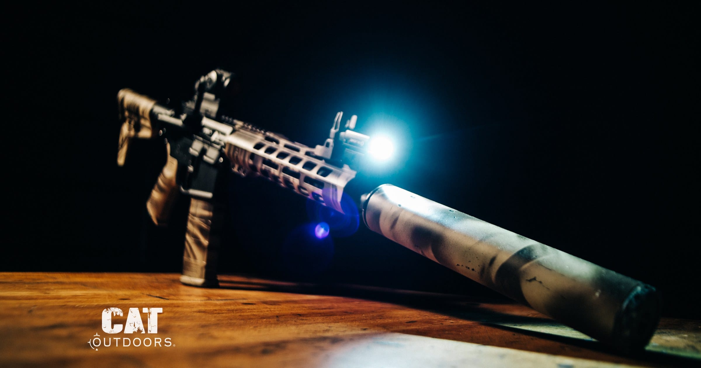 Camo AR pistol with suppressor and weapon light on a dark background
