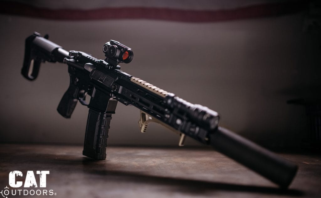 Suppressed 300 Blackout AR pistol with a red dot optic on a dark bench