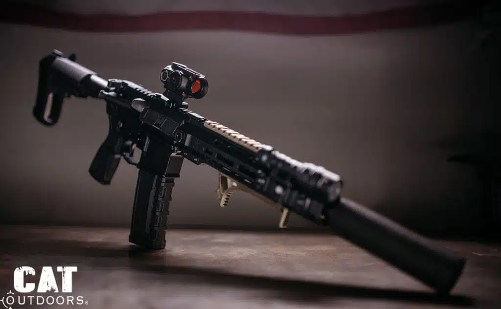 Suppressed 300 Blackout AR pistol with a red dot optic on a dark bench