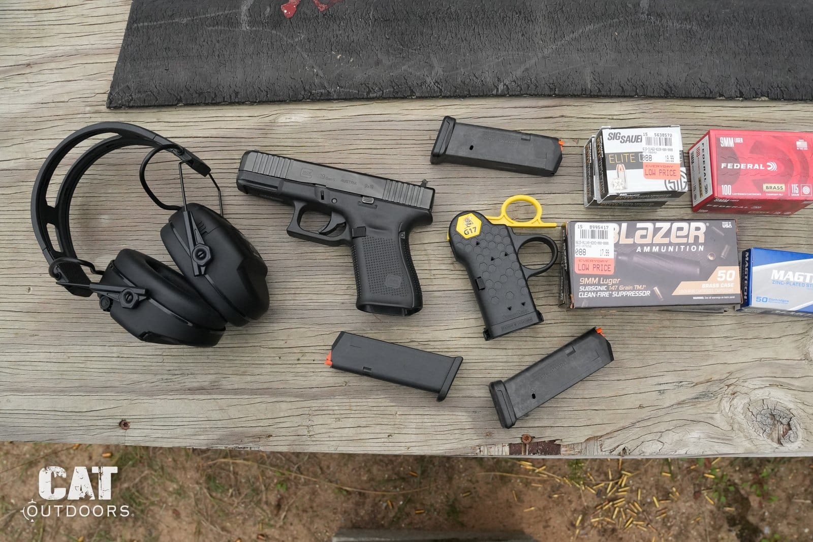 Range bench with the Glock 19 Gen 5, four magazines, a chamber flag, ear protection and the ammo loads tested
