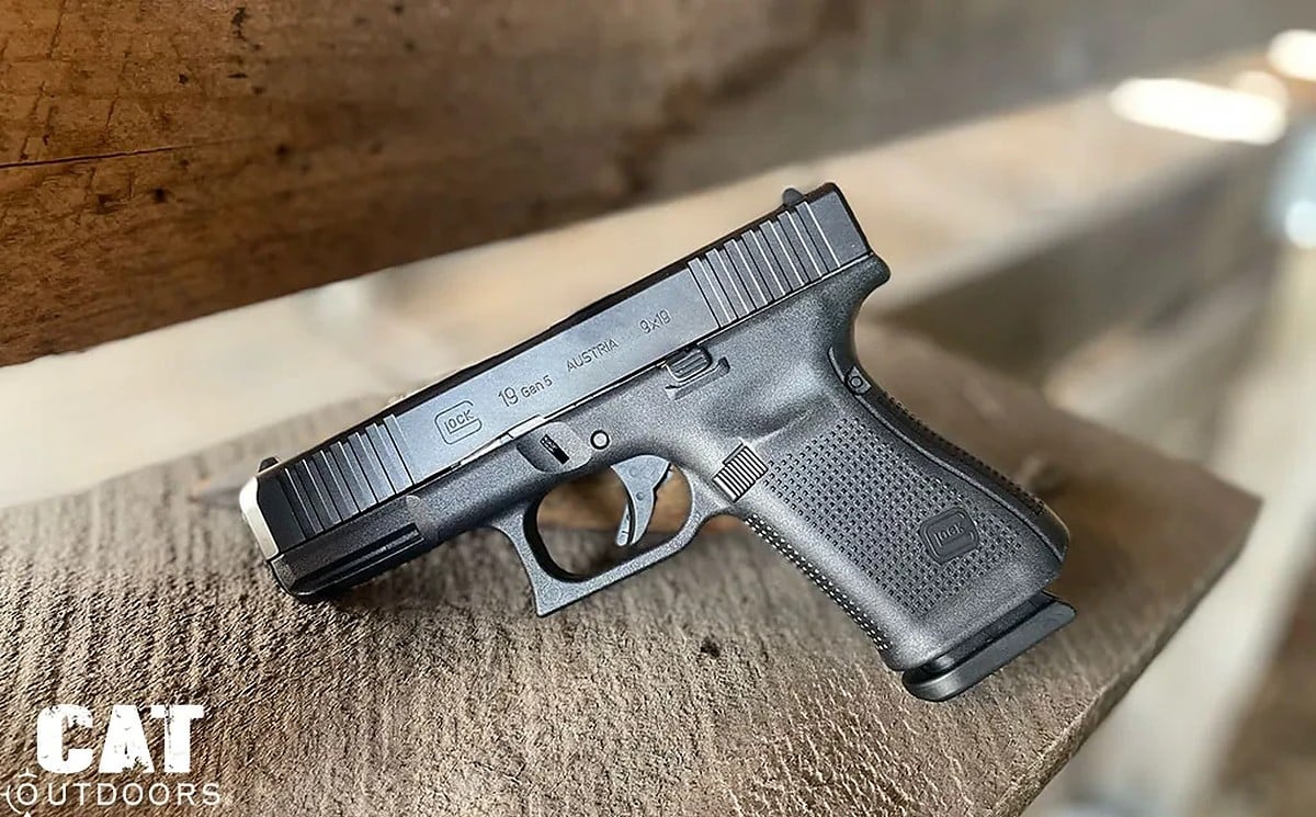 Glock 19 Gen 5 on a barn-wood bench, left side, showing the 19 Gen5 Austria slide marking