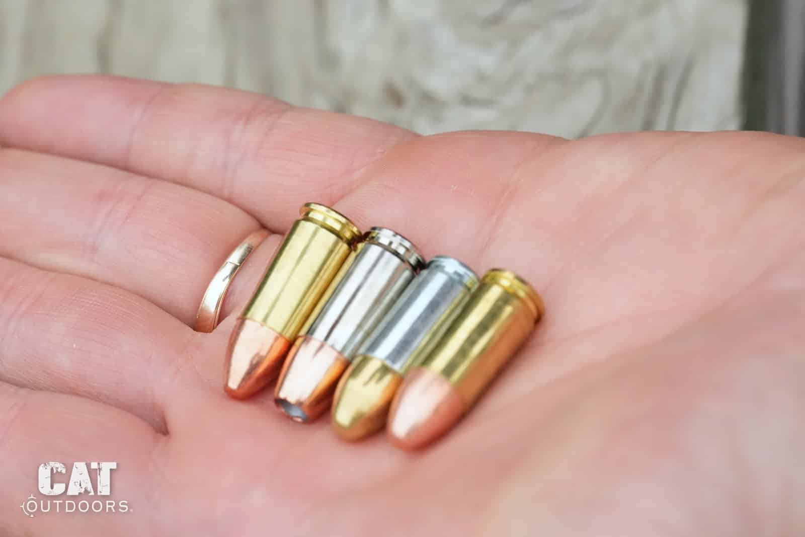 The four loads rotated through one magazine, held in a palm: brass hollow point, nickel case, steel case and brass full metal jacket