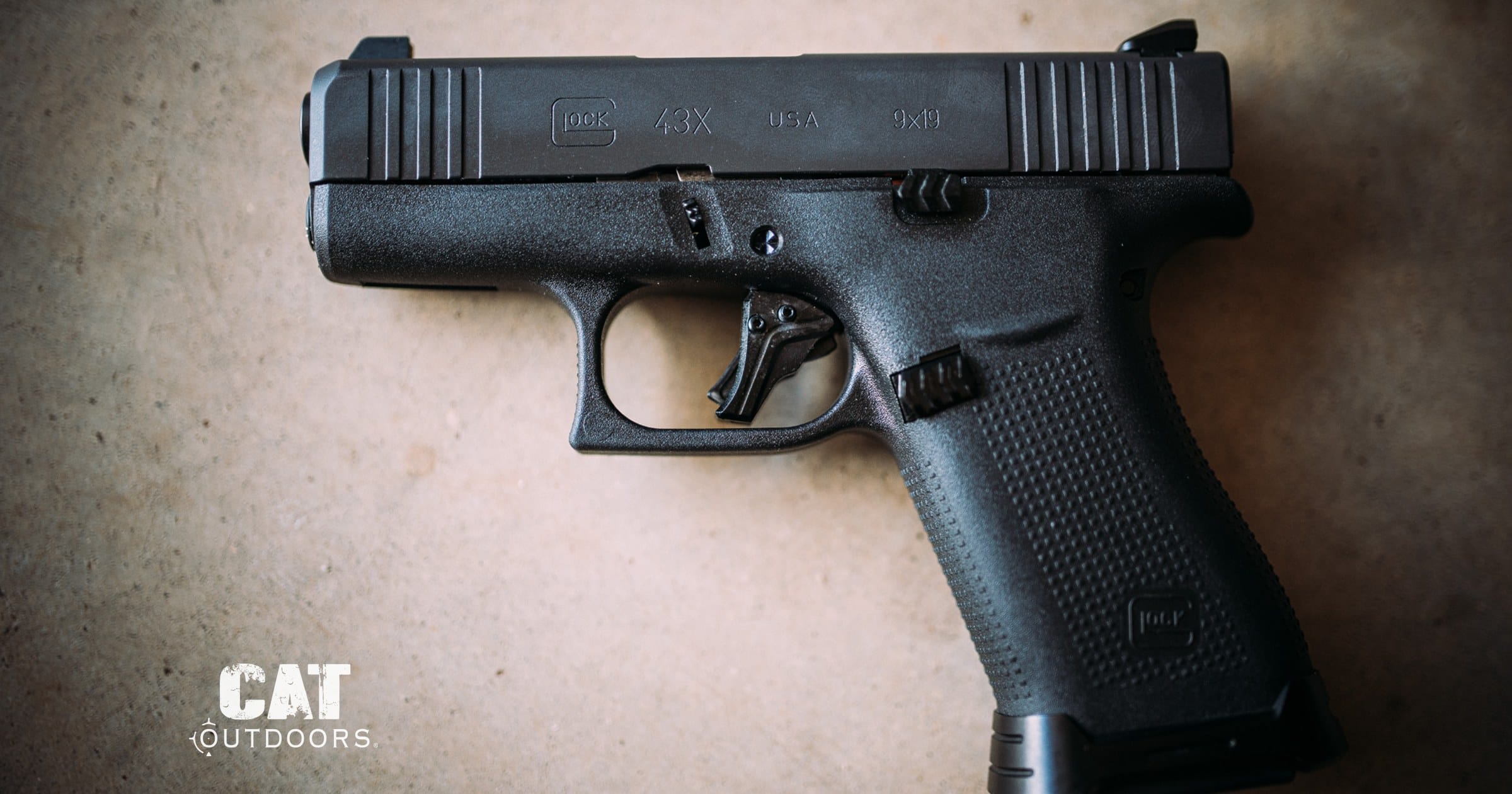 Glock 43X pistol on concrete with the trigger and safety blade visible