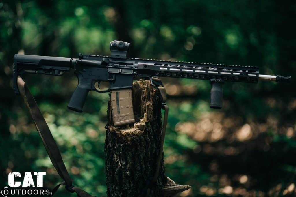 AR-15 rifle resting on a tree stump with the safety selector and trigger visible