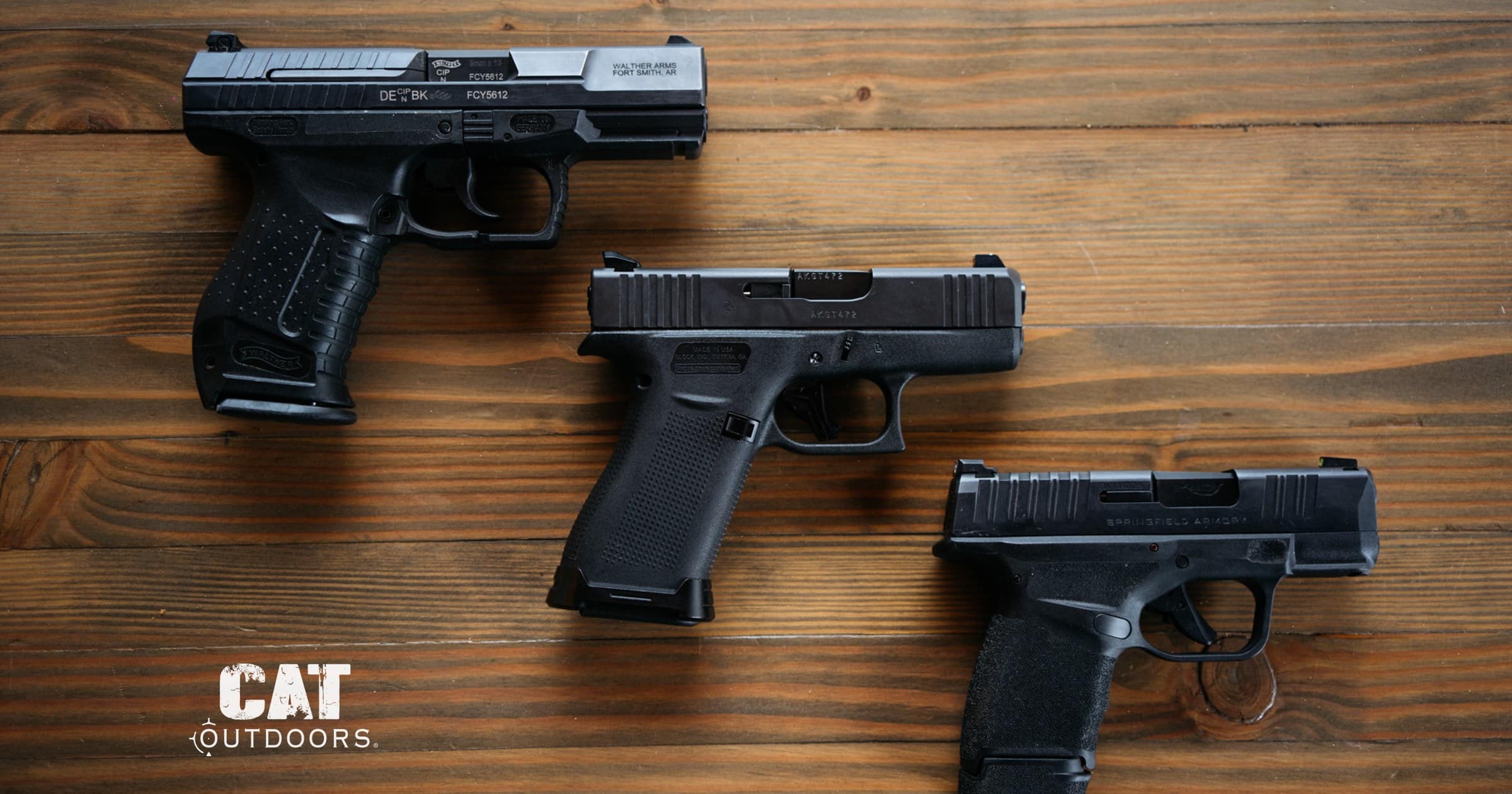 Three 9mm carry pistols laid out on a wood workbench