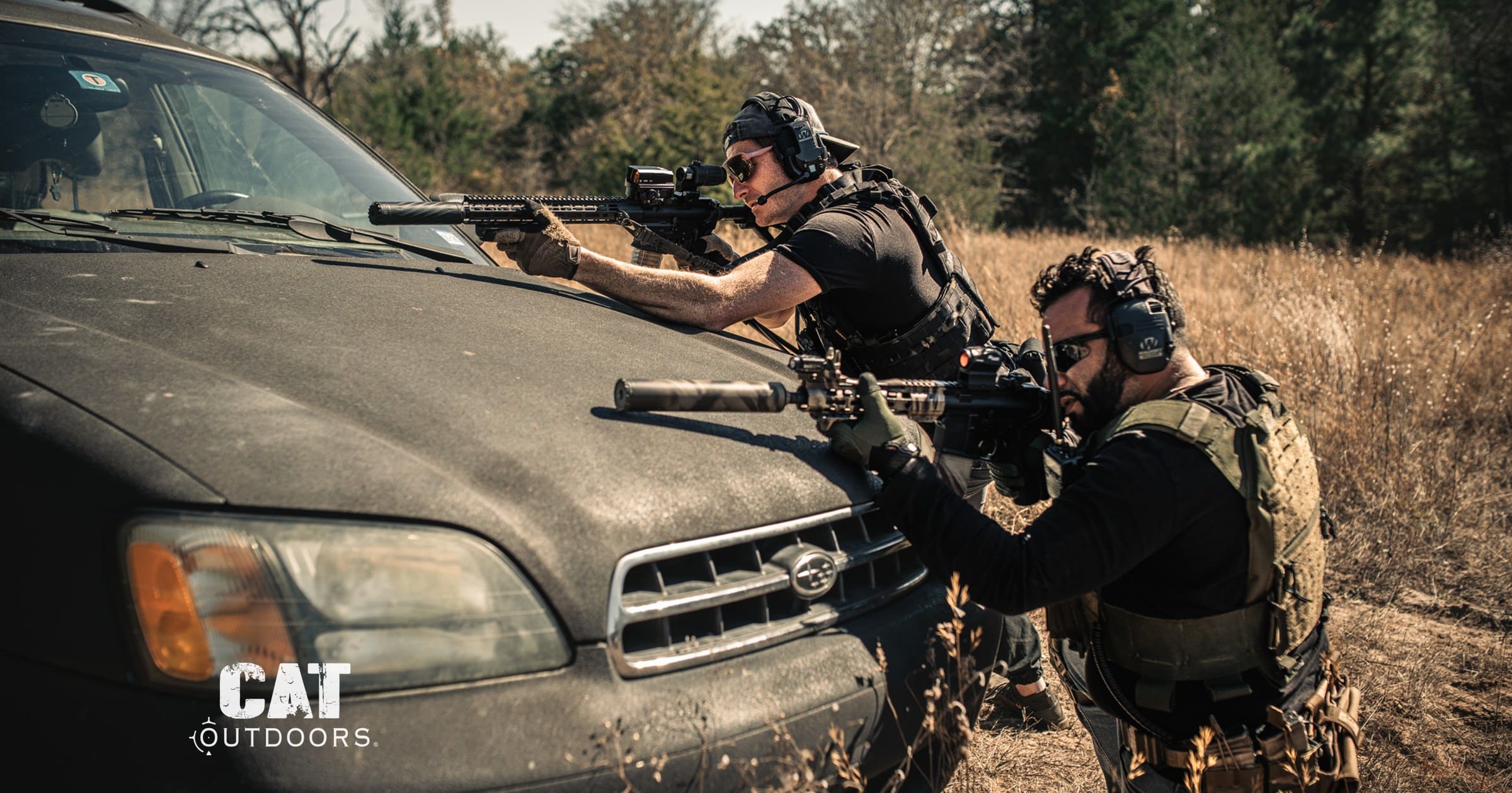 Two shooters firing suppressed AR-15 rifles over the hood of a car