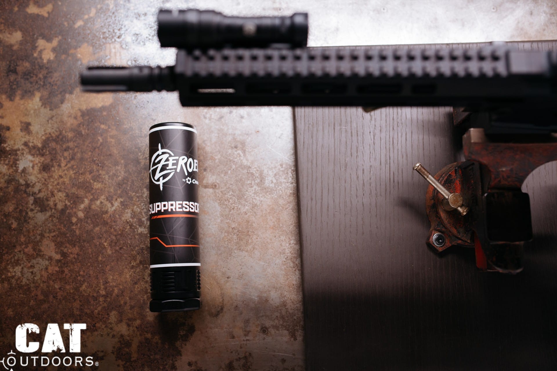 A new suppressor in its shipping tube next to an AR-15 on a workbench