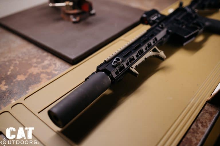 Suppressed AR-15 upper resting on a tan bench mat